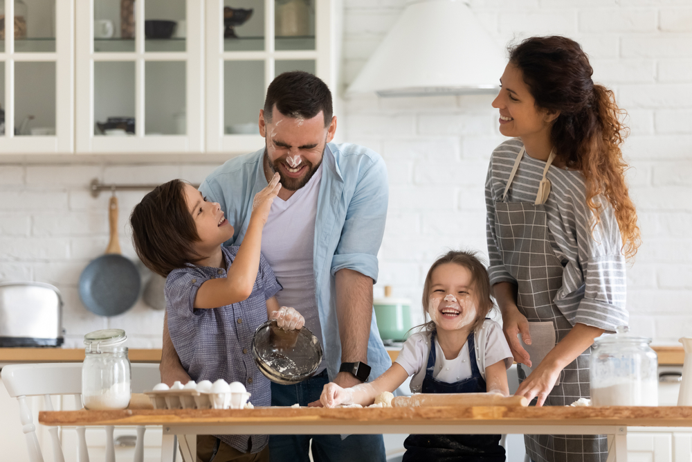 A happy family of four playfully baking together in a bright kitchen