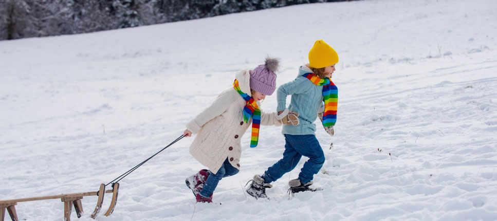 Children pulling a sleigh in a snowy ground