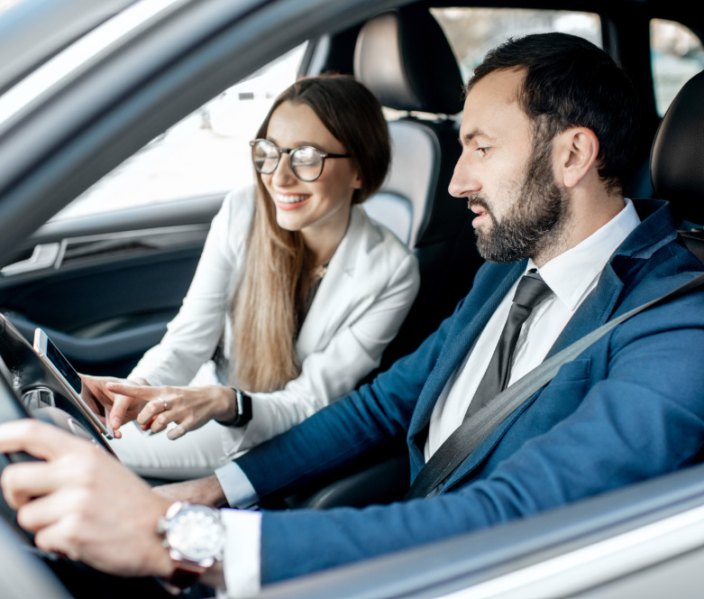 Man in business suit driving a car with a lady Man in business suit driving a car with a lady