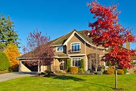 A picturesque home surrounded by a spacious yard featuring a vibrant red tree in the foreground A picturesque home surrounded by a spacious yard featuring a vibrant red tree in the foreground